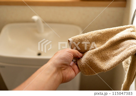 トイレタンクの手洗い水で手を洗ってタオルで手を拭く 115047383