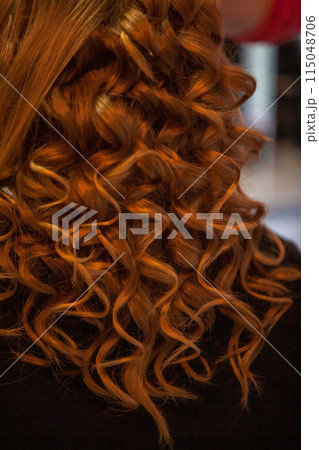An upclose view of luxuriant, curly ginger hair illuminated by a warm, cozy light 115048706