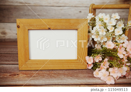 Empty Photo frame mock up with flower bouquet decoration on wooden background 115049513