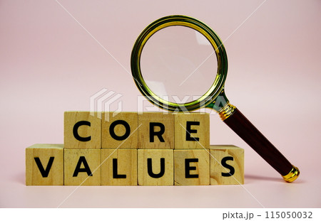 Core Values with wooden blocks alphabet letters and Magnifying glass on pink background 115050032