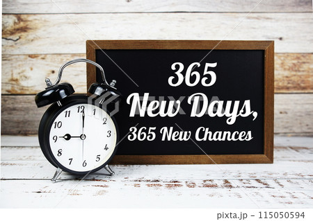 Inspirational quote 365 New Days 365 New Chances text message written on chalkboard with alarm clock on wooden background 115050594