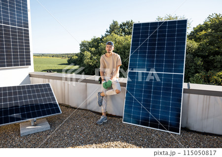 Man installing solar panels on a rooftop Man installing solar panels on a rooftop 115050817