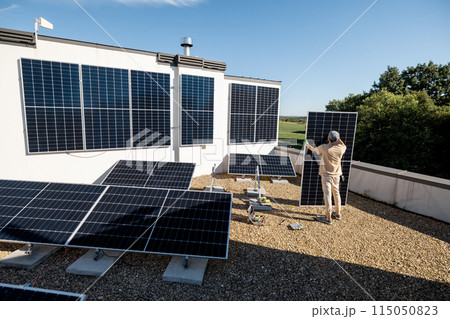 Man installing solar panels on a rooftop 115050823
