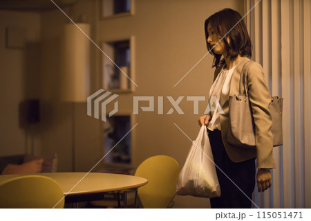 帰宅後リビングでジャケットを脱ぐビジネスウーマンのナイトルーティーン　 115051471