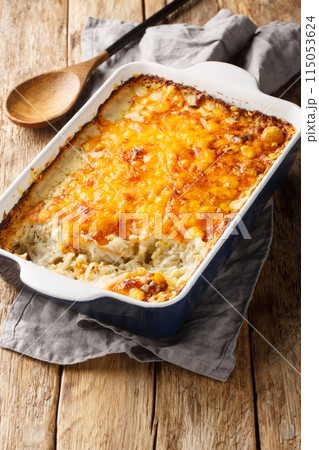 Hashbrown casserole with thickened creamy chicken soup and cheddar cheese close-up in a baking dish. Vertical Hashbrown casserole with thickened creamy chicken soup and cheddar cheese close-up in a baking dish. Vertical 115053624