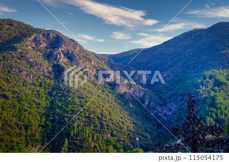 Experience the breathtaking valley view in the sunlight, surrounded by mountains and greenery 115054175