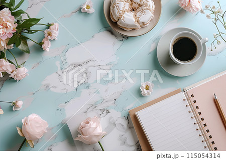 Flat lay table with a cup of coffee, a pastry, and open notebook with copy space. The table is decorated with flowers 115054314