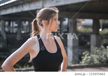 Young woman doing gymnastics on the street. Portrait of fit and sporty young woman doing stretching in city. 115055662