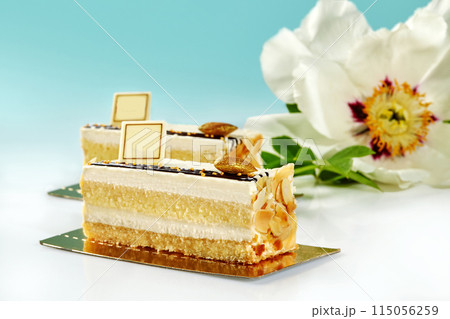 Slices of sponge cake with vanilla cream and almond on blue background 115056259