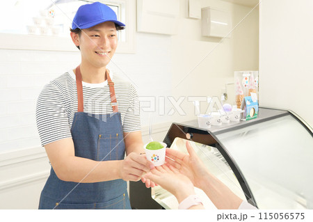 お客にジェラートを手渡す男性販売スタッフ 115056575