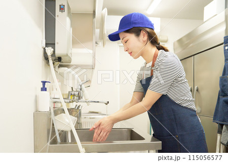 キッチンで手を洗うエプロン姿の女性スタッフ キッチンで手を洗うエプロン姿の女性スタッフ 115056577
