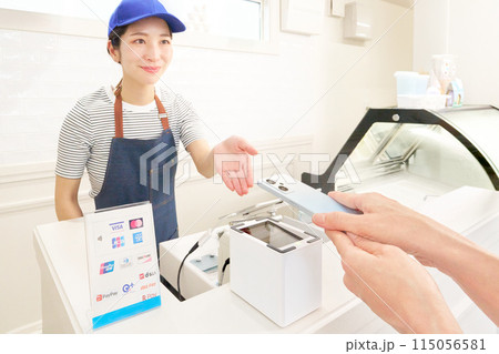 キャッシュレス決済をするお客の手元と案内する女性店員 115056581