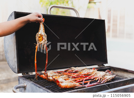 Grills king prawns on charcoal grill in the restaurant. Grills king prawns on charcoal grill in the restaurant. 115056905