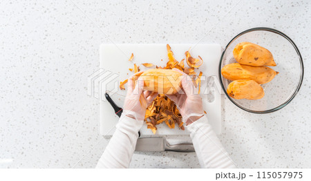 Flat lay. Peeling sweet potatoes with potato peeler to make oven-roasted sweet potatoes 115057975