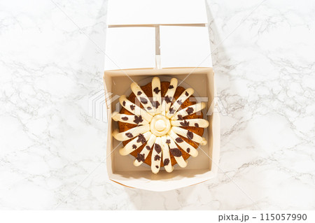 Flat lay. Packaging the freshly baked pumpkin bundt cake into a white paper box for gifting. Flat lay. Packaging the freshly baked pumpkin bundt cake into a white paper box for gifting. 115057990