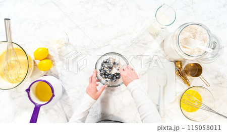 Flat lay. Integrating ingredients in a glass bowl, adeptly stirring with a whisk to craft a tantalizing lemon-blueberry bundt cake. Flat lay. Integrating ingredients in a glass bowl, adeptly stirring with a whisk to craft a tantalizing lemon-blueberry bundt cake. 115058011