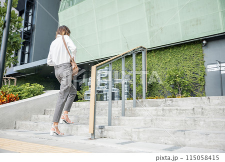 A businesswoman, sporting a modern suit, embodies determination while climbing city stairs. Her black shoe-clad foot is the emblem of unceasing effort, marking the journey toward success and progress. A businesswoman, sporting a modern suit, embodies determination while climbing city stairs. Her black shoe-clad foot is the emblem of unceasing effort, marking the journey toward success and progress. 115058415