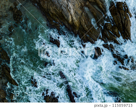 Bird eye view seashore with big wave crashing on rock cliff. Beautiful waves sea surface in sunny day summer background, Amazing seascape top view seacoast landscape view Bird eye view seashore with big wave crashing on rock cliff. Beautiful waves sea surface in sunny day summer background, Amazing seascape top view seacoast landscape view 115059713