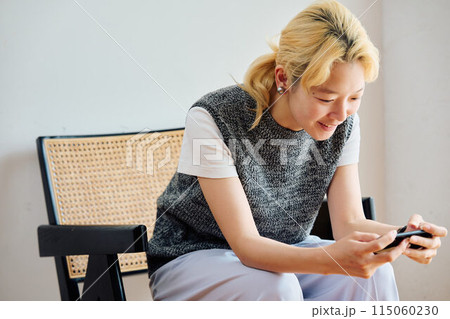 部屋でスマホを操作する女性 115060230