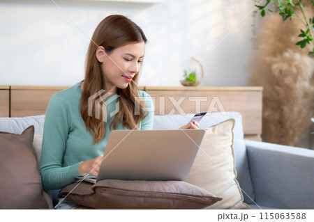 Young asian woman sitting on sofa using laptop computer shopping online with credit card. Young asian woman sitting on sofa using laptop computer shopping online with credit card. 115063588