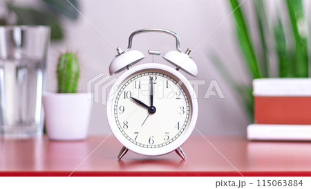 Classic white clock on a table. The clock hand points at 10,00 or 22,00 close up photo interior 115063884