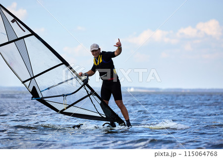 Young man surfing the wind in splashes of water Young man surfing the wind in splashes of water 115064768