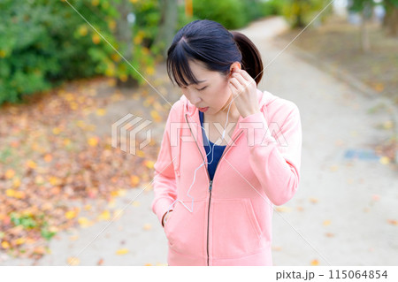 有線イヤホンで音楽を聴きながらウォーキングする若い女性 ボディメイク トリミングアップ 有線イヤホンで音楽を聴きながらウォーキングする若い女性 ボディメイク トリミングアップ 115064854