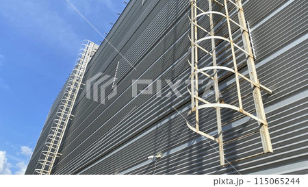 Emergency fire ladder escapes on gray wall of building, safe evacuation exit in case of emergency 115065244
