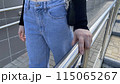 Young woman in jeans holds her hand on metal handrail on street ramp, woman hand grabs for balance on the stairs 115065267