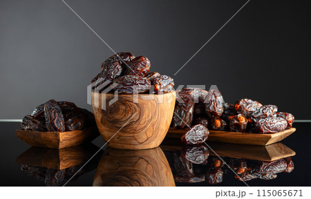 Dates in wooden dish on a black background. Dates in wooden dish on a black background. 115065671