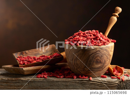 Dried goji berries in wooden bowl on a brown background. 115065698