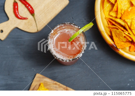 Michelada cocktail with tomato juice, beer and lime in a glass and nachos. Selective focus Michelada cocktail with tomato juice, beer and lime in a glass and nachos. Selective focus 115065775