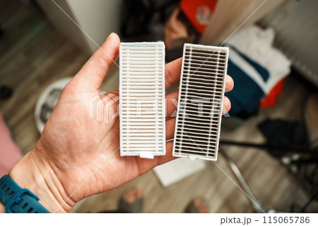 Robot vacuum filters lit home, showcasing the contrast between a pristine, clean filter and a used, dust-laden one 115065786
