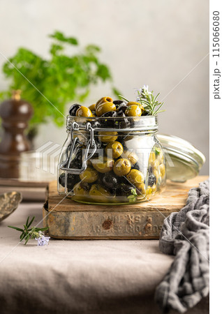 Green and black olives mix, in a glass jar. Delicious, marinated olives. Green and black olives mix, in a glass jar. Delicious, marinated olives. 115066080