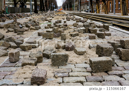 Historic cube-shaped hammered natural granite paving stones on an unfinished street pavement 115066167
