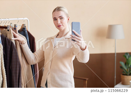Waist up portrait of blonde young woman giving fashion advice and recording video with mobile phone, copy space Waist up portrait of blonde young woman giving fashion advice and recording video with mobile phone, copy space 115066229