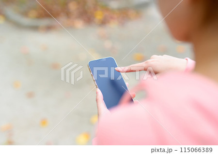 スマホを見ながらウォーキングする若い女性 ボディメイク ランニングウェア スマホを見ながらウォーキングする若い女性 ボディメイク ランニングウェア 115066389