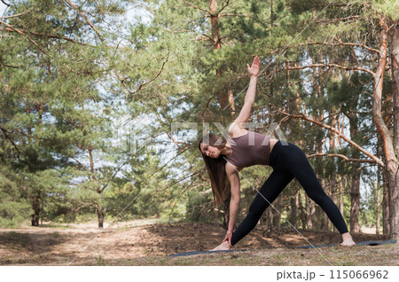 A young attractive woman in sportswear practices yoga in the forest. A young attractive woman in sportswear practices yoga in the forest. 115066962