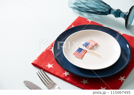 American table setting with USA flags and decoration in national flag colors on blue background. Independence Day. Happy Memorial Day. Close up. Copy space 115067495