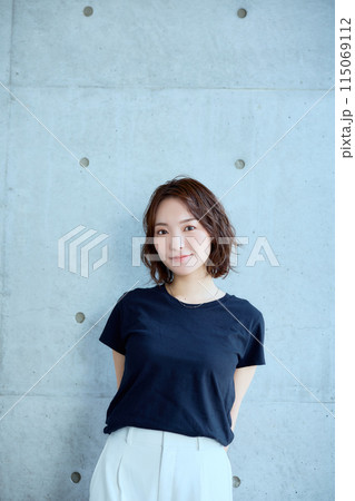 コンクリート背景に立つ女性のポートレート 115069112