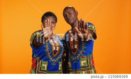 Serious african american couple show stop sign on camera, raising palm and expressing their refusal. Man and woman doing rejection gesture and being displeased about something, disagreement. 115069169