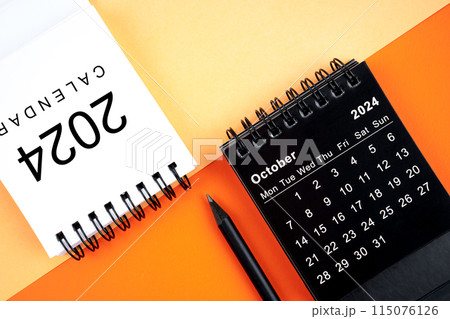 October 2024 desk calendar black and white color with pencil on orange background. October 2024 desk calendar black and white color with pencil on orange background. 115076126