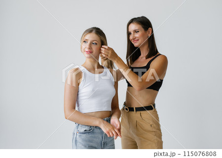 Hair stylist corrects a model's hairstyle on a white background in the studio 115076808