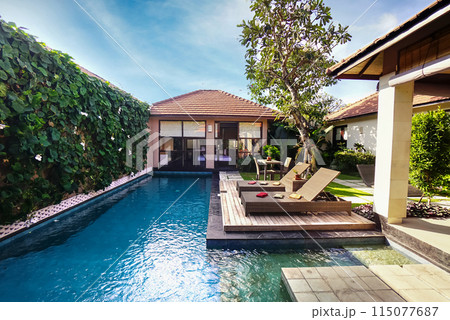 Beautiful contemporary home with pool and tropical ornament and plants pool with view of tropical blue water in clean garden Beautiful contemporary home with pool and tropical ornament and plants pool with view of tropical blue water in clean garden 115077687
