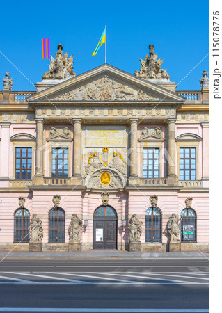 The German Historical Museums grand facade bathes in sunlight against a clear blue sky on Unter den Linden Street in Berlin, Germany 115078776