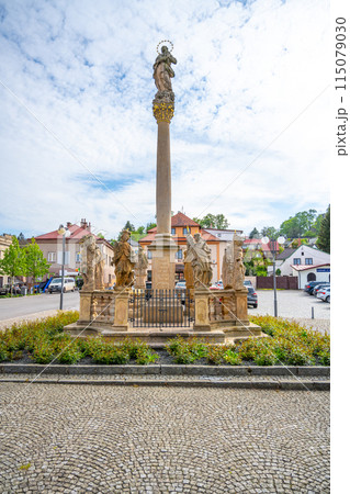 A stone plague column stands in the center of Pecka town square in the Czech Republic. The column is topped with a statue and surrounded by smaller statues. A stone plague column stands in the center of Pecka town square in the Czech Republic. The column is topped with a statue and surrounded by smaller statues. 115079030