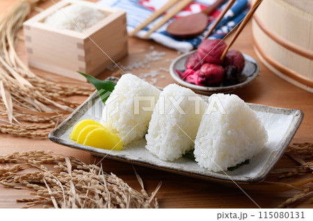 炊き立てのごはんで作ったおにぎり（塩むすび）と枡に盛ったお米と梅干し 115080131