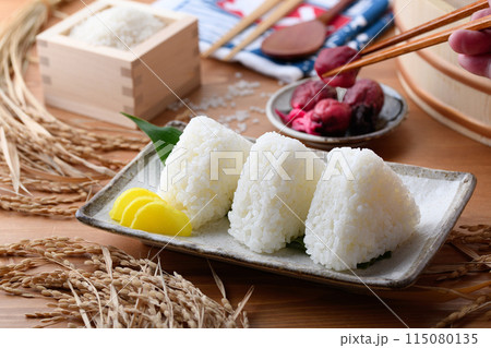 炊き立てのごはんで作ったおにぎり（塩むすび）と枡に盛ったお米と梅干し 115080135