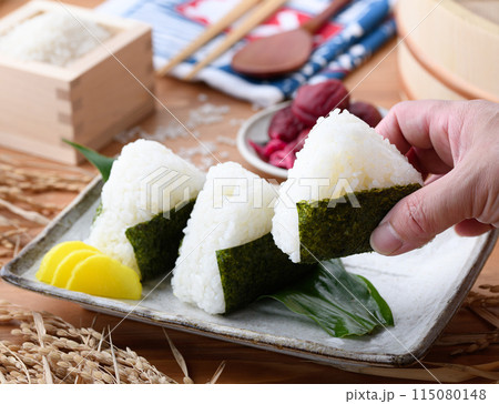 炊き立てのごはんに海苔を巻いたおむすびと、枡に盛ったお米と梅干し 炊き立てのごはんに海苔を巻いたおむすびと、枡に盛ったお米と梅干し 115080148