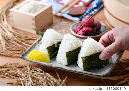 炊き立てのごはんに海苔を巻いたおむすびと、枡に盛ったお米と梅干し 炊き立てのごはんに海苔を巻いたおむすびと、枡に盛ったお米と梅干し 115080149